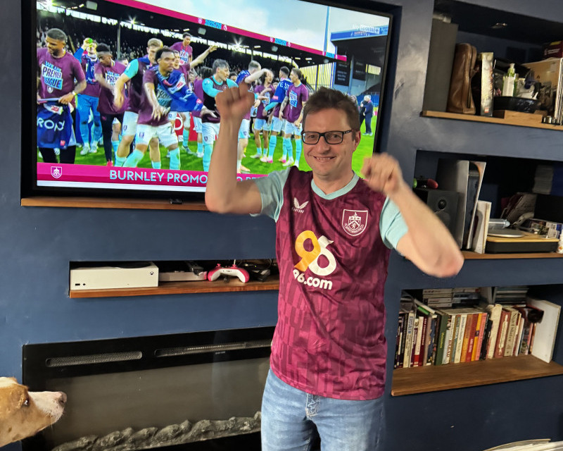 Photo of me wearing a Burnley home shirt in front of the Bob Lord Stand on TV