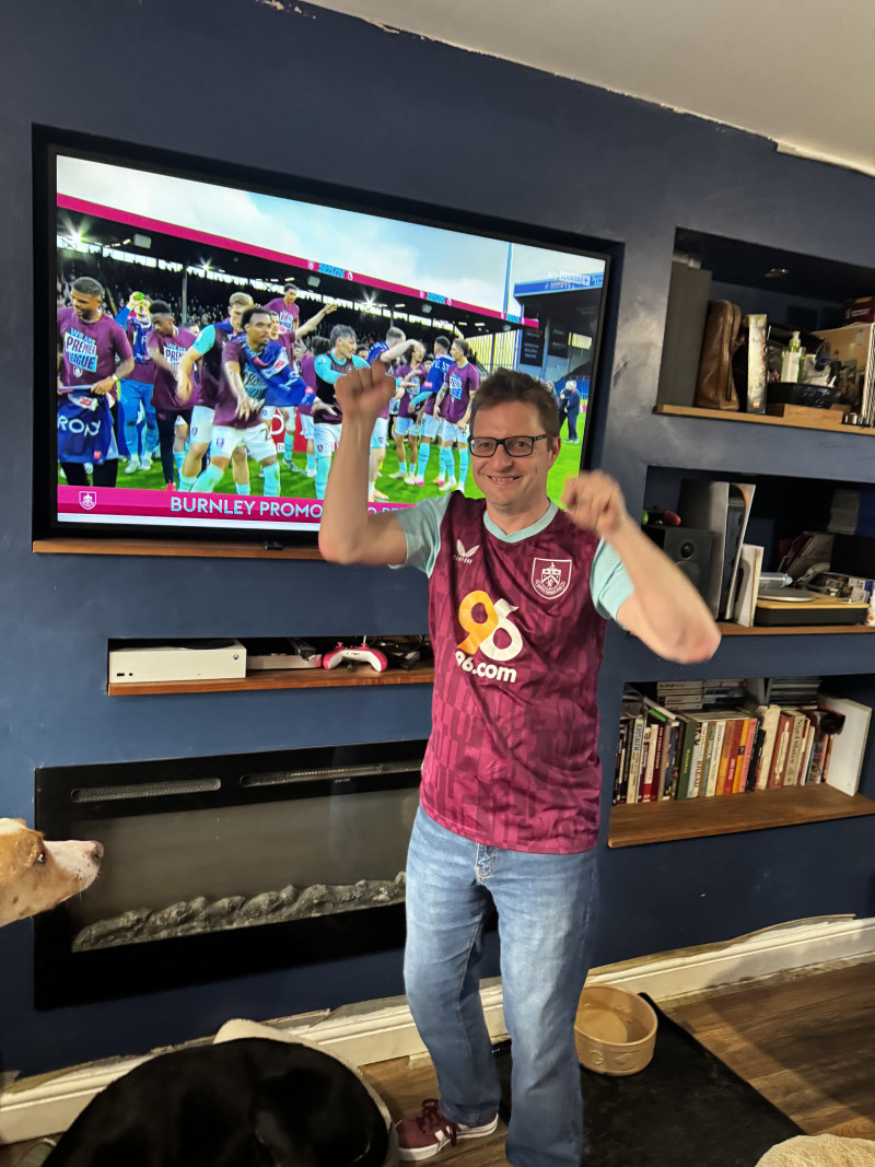 Photo of me wearing a Burnley home shirt in front of the Bob Lord Stand on TV
