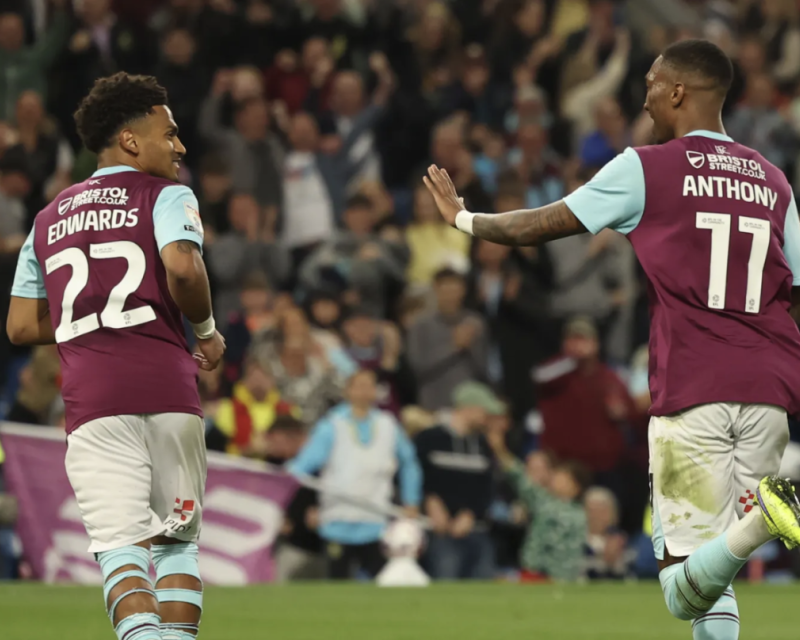 Image of Marcus Edwards and Jaidon Anthony running away from the camera and looking towards each other in 2024-5 season home kit, Edwards wearing number 22, and Anthony 11.
