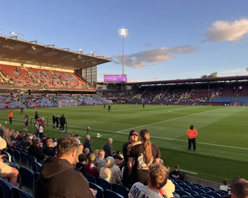 Turf Moor stadium under the floodlights on a sunny evening
